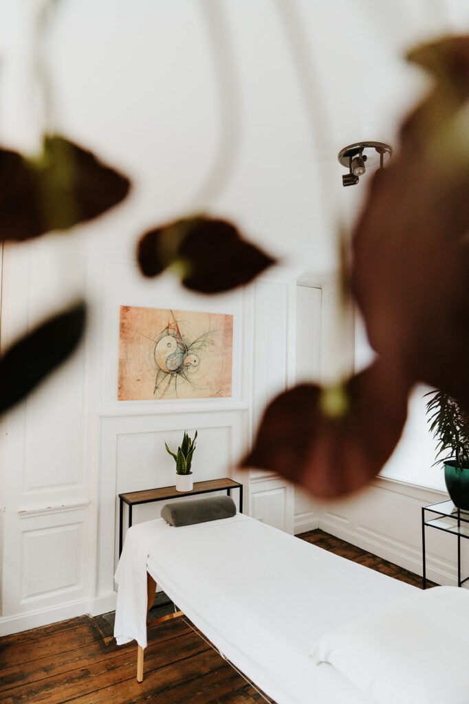 A treatment room at Soma Wellbeing Centre, viewed through plant leaves