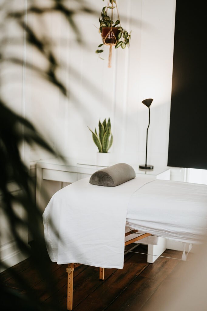 A treatment room at Soma Wellbeing Centre in soft daylight, seen past a plant