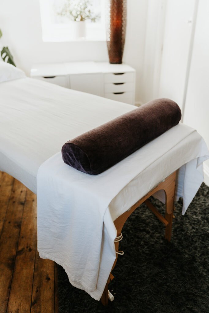 A massage table with a bolster and fresh linen in a treatment room at Soma Wellbeing Centre